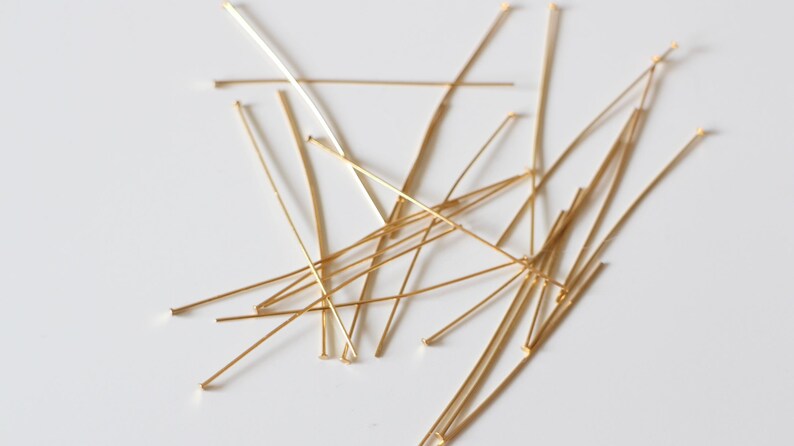 Pu&ograve; includere: Un mucchio di spilli per la testa dorati, utilizzati per la creazione di gioielli e l'artigianato.