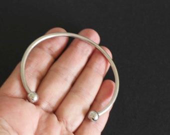 Puede incluir: Un brazalete de plata con dos extremos redondos.