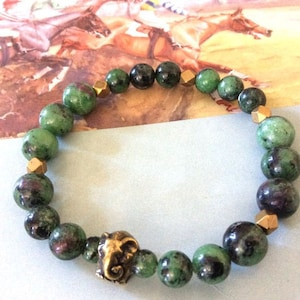 May include: A green and black gemstone bracelet with gold accents and an elephant charm.