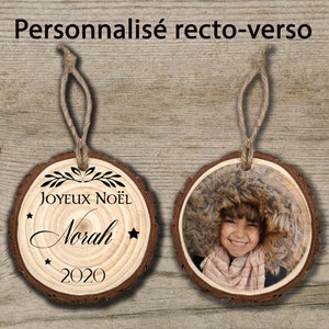May include: A personalised wooden Christmas bauble with a photo on one side and the text "Joyeux No&euml;l Norah 2020" on the other side.