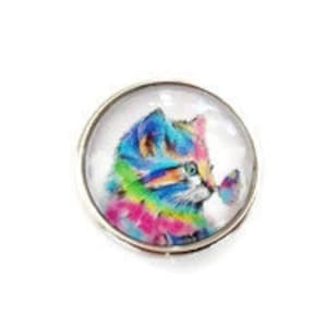 Puede incluir: Un cabujón de vidrio colorido con un diseño de gato arcoíris y una mariposa azul. El gato mira hacia la derecha y tiene un fondo blanco.