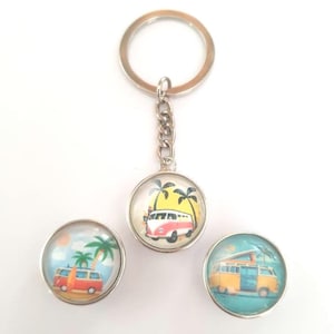 Peut inclure: Un ensemble de trois porte-clés représentant un camping-car vintage avec des palmiers et une scène de plage. Les porte-clés sont ronds et ont une finition de type verre. Le camping-car est blanc avec des accents rouges et jaunes. Les porte-clés sont attachés à des anneaux de clés argentés.
