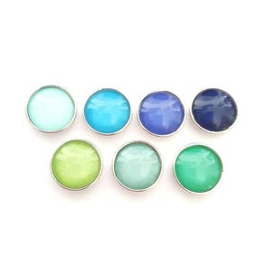 Puede incluir: Surtido de ocho cabujones redondos, de fondo plano, de colores vivos. Los cabujones están engastados en engastes de metal plateado. Los colores incluyen azul claro, turquesa, azul, azul oscuro, verde claro, verde y amarillo.