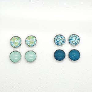 Puede incluir: Seis pares de pendientes con diferentes diseños. Dos pares presentan un patrón floral azul y blanco, dos pares presentan un color azul claro sólido y dos pares presentan un color verde claro sólido.