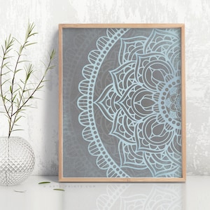 Puede incluir: Una impresi&oacute;n enmarcada de un dise&ntilde;o de mandala azul y gris. El mandala es un patr&oacute;n circular con intrincados detalles. La impresi&oacute;n est&aacute; enmarcada en un marco de madera claro.