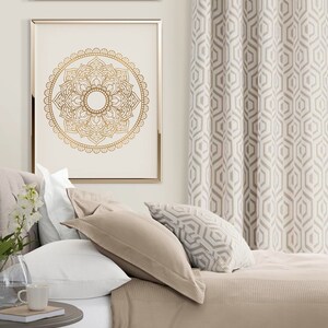 May include: A beige bed with white bedding and two gold framed pictures with mandala designs. The bed has a beige throw blanket and a patterned pillow. The curtains are a geometric pattern in beige and white.