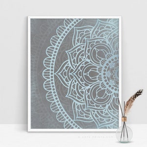 Puede incluir: Un dise&ntilde;o de mandala azul claro sobre un fondo gris. El mandala es un patr&oacute;n circular con intrincados detalles. El dise&ntilde;o est&aacute; enmarcado en un marco blanco.
