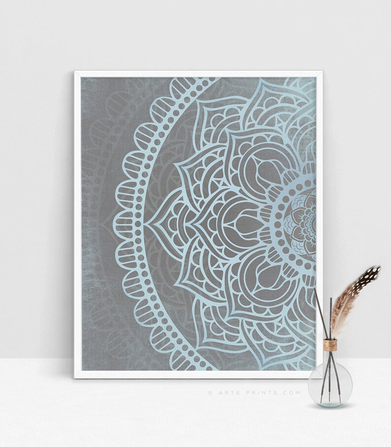 Puede incluir: Un dise&ntilde;o de mandala azul claro sobre un fondo gris. El mandala es un patr&oacute;n circular con intrincados detalles. El dise&ntilde;o est&aacute; enmarcado en un marco blanco.