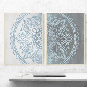 Puede incluir: Dos impresiones enmarcadas de dise&ntilde;os de mandalas azules y grises. Los mandalas son intrincados y detallados, con un patr&oacute;n circular de flores y hojas. Las impresiones son perfectas para agregar un toque de estilo bohemio a cualquier habitaci&oacute;n.