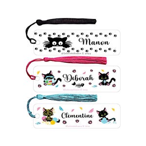 Peut inclure: Trois marque-pages blancs avec des illustrations de chats noirs et des noms personnalisés. Le marque-page du haut présente un chat noir avec un motif de pattes et le nom "Manon". Le marque-page du milieu présente un chat noir portant un bandana bleu et vert à motifs et le nom "Deborah". Le marque-page du bas présente un chat noir portant une écharpe bleue et rose à motifs et le nom "Clémentine".