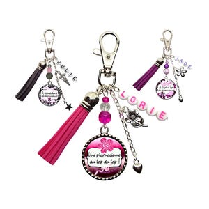 Peut inclure: Porte-clés rose et violet avec des breloques et des pompons. Un porte-clés a un charme avec le texte "A la meilleure des pharmaciennes au top du top!" Un autre porte-clés a un charme avec le texte "JULIE". Le troisième porte-clés a un charme avec le texte "LORIE".