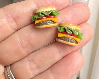 Può includere: Due orecchini a forma di mini hamburger. Ogni piccolo hamburger presenta un panino al sesamo, lattuga, pomodoro, formaggio e un hamburger di manzo. Gli orecchini sono piccoli e dettagliati, perfetti per gioielli a tema cibo.