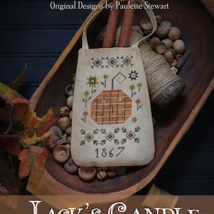 May include: A white linen sampler with a stitched image of a pumpkin with a face, surrounded by sunflowers and leaves. The sampler is dated 1867 and is titled "Jack's Candle Pocket".