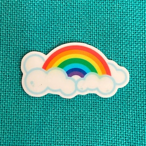 May include: A rainbow sticker with a white cloud. The rainbow has red, orange, yellow, green, blue, indigo, and violet stripes.