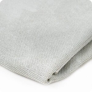 Puede incluir: Primer plano de una tela tejida de color gris claro. La tela tiene una textura sutil y un acabado liso.