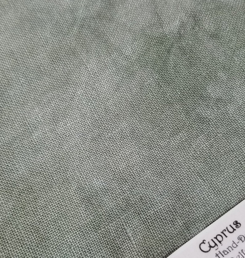 Puede incluir: Primer plano de una tela verde texturizada con una etiqueta blanca que dice "Cyprus Hand-Dyed 21f"