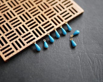 May include: A group of ten small, teardrop-shaped charms with a gold loop at the top. The charms are a bright turquoise blue color.