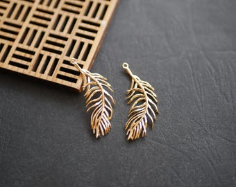 May include: Two gold-colored metal feather charms with a loop at the top for attaching to jewelry or other crafts.