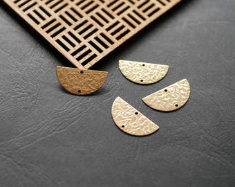 May include: Four gold-coloured metal half-circle shapes with a textured surface. The shapes are arranged in a semi-circle pattern on a dark grey surface.