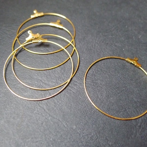 Peut inclure: Quatre créoles dorées avec une fermeture à fermoir. Les créoles sont empilées les unes sur les autres.