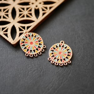 Peut inclure: Deux boucles d'oreilles en métal doré avec un motif géométrique coloré. Les boucles d'oreilles sont rondes et ont une frange de petites boucles autour du bord.