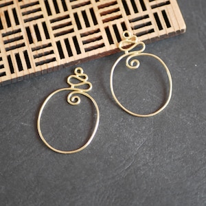 Peut inclure: Deux boucles d'oreilles créoles en fil d'or avec un motif décoratif en fil de fer au sommet de chaque créole.