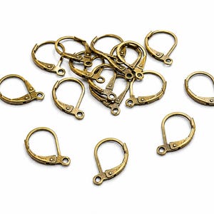 Könnte beinhalten: Eine Sammlung von Ohrring-Rohlingen aus antik bronzefarbenem Metall mit einem Klappbügel-Verschlussmechanismus. Jedes Teil besteht aus einem kreisförmigen Bügel mit einem Scharnierverschluss und einer kleinen Öse an der Basis für Anhänger.