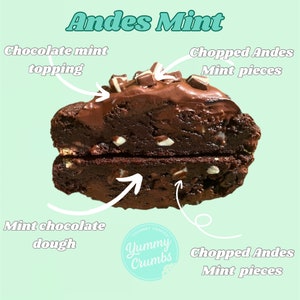 May include: A chocolate chip cookie with Andes mint pieces and chocolate mint topping. The cookie is cut in half to show the mint chocolate dough inside. The cookie is labeled "Yummy Crumbs."
