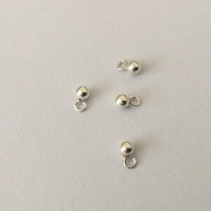 Puede incluir: Cuatro tapones de bola de plata con un bucle en la parte superior. Se utilizan para la fabricación de joyas.
