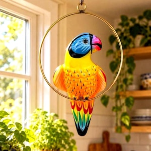 May include: A hanging parrot ornament featuring a bright yellow chest, a blue head, and a red and green tail, suspended within a circular gold-toned metal ring that is attached to a chain for ceiling mounting.