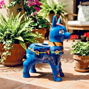 May include: A vibrant blue ceramic donkey planter with decorative floral patterns in yellow, red, and green. The donkey has a yellow and orange collar and is surrounded by potted plants, creating a colorful outdoor scene.