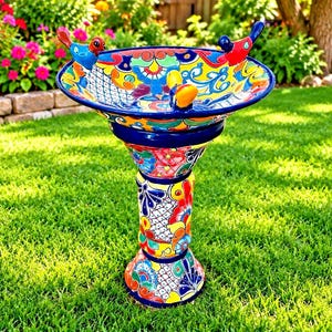 May include: A hand-painted ceramic birdbath featuring a vibrant, multi-colored floral and geometric pattern. The basin has a wide, circular rim with three small, colorful bird figurines attached to the edge, supported by a sturdy, matching pedestal base.