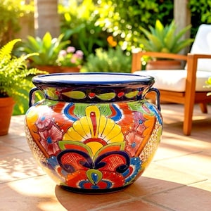 May include: A large, round ceramic planter featuring a vibrant, hand-painted floral pattern in shades of yellow, red, blue, and green. The pot has a wide, dark blue rim, two side handles, and a glossy finish, showcasing intricate, colorful designs.