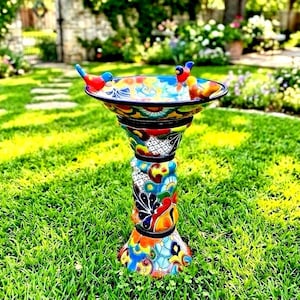 May include: A ceramic birdbath featuring a vibrant, multi-colored hand-painted floral and geometric pattern. The basin is supported by a pedestal base and includes three small, colorful bird figurines attached to the rim of the bowl.