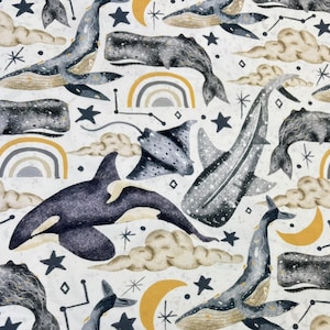 May include: A white fabric with a repeating pattern of whales, manta rays, and stars. The whales are gray and white, the manta rays are gray, and the stars are black. There are also yellow crescent moons and rainbows in the pattern.
