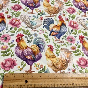 May include: A white fabric with a repeating pattern of colorful roosters and floral designs. The roosters are in various poses, some with their wings spread and others with their tails raised. The flowers are in shades of pink, purple, and yellow.