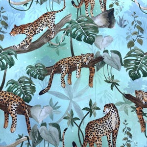 May include: A fabric pattern featuring multiple leopards in a jungle setting. The leopards have brown spots on a tan coat and are positioned on tree branches and the ground. The background is a light blue with green foliage.