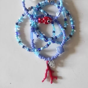 Peut inclure: Un ensemble de bracelets de perles superposés dans des tons bleus, comprenant de petites perles en verre, une perle rouge en forme de poisson à pois blancs, une perle rayée bleu et blanc en forme de coquillage et une breloque corail rouge.