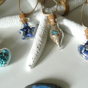 May include: Four glass bottle necklaces with different colored stones inside. The bottles are hanging from a white starfish.