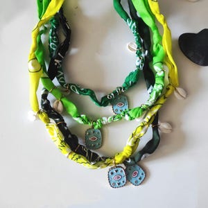 Bandana necklace in various colors with a pink or blue seashell medallion and seaside charms, or bandana bracelet wrapped around several times.