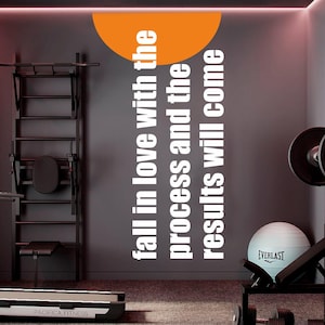 May include: A gym interior with exercise equipment, including a pull-up bar, weight bench, and a treadmill. The wall features the text "fall in love with the process and the results will come" in white. An orange semi-circle is at the top.