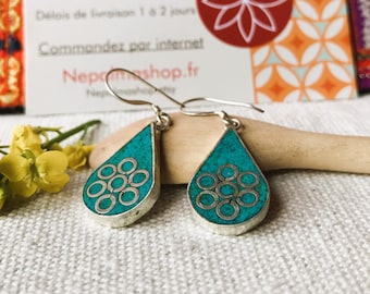 May include: Teal blue teardrop shaped earrings with silver accents and a circular pattern. The earrings have a hook closure.