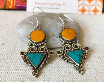 May include: Silver dangle earrings with turquoise and amber stones. The earrings feature a triangular design with intricate details.