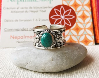 May include: Silver ring with a green gemstone set in a silver band. The band is decorated with small silver beads and a braided design.
