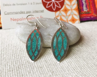May include: A pair of silver-toned earrings with a leaf-like shape. Each earring features a teal glitter-filled design within a silver frame. The earrings are displayed on a white surface.