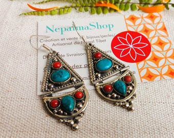May include: Silver earrings featuring turquoise and coral stones. The earrings are shaped like a triangle with a crescent moon shape underneath. The earrings are handcrafted in Nepal.