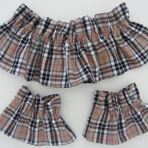 Peut inclure: Ensemble de trois pièces de tissu à volants avec un motif à carreaux classique. La pièce principale est une large volants froncés, avec deux petites pièces à volants assorties. Le motif à carreaux comprend des lignes beiges, noires, blanches et rouges.