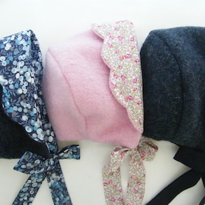 Peut inclure: Trois bonnets avec un extérieur en laine texturée et une doublure en tissu à motifs. Le bonnet de gauche est gris foncé avec une doublure à fleurs bleues, celui du centre est rose clair avec un petit imprimé floral, et celui de droite est gris foncé.