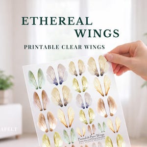May include: A hand holds a sheet of printable clear wings in shades of green, yellow, and brown. The image features the text "ETHEREAL WINGS" and "PRINTABLE CLEAR WINGS" at the top, with a soft, blurred background.