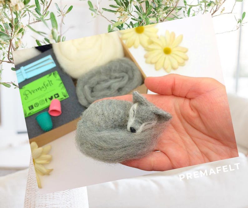 In the picture, a fluffy wool toy wolf lies curled up in a person's palm.